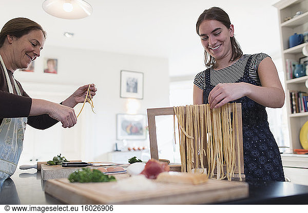 Mother and daughter making fresh homemade pasta in kitchen