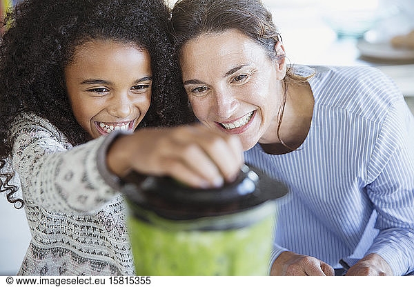 Mother and daughter making healthy green smoothie in blender
