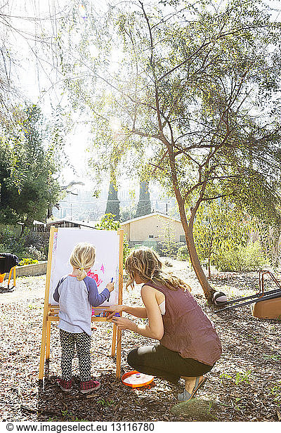 Mother and daughter painting in backyard