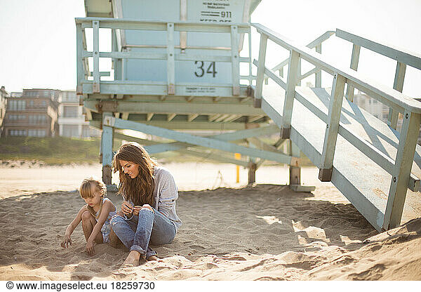 Mother and daughter playing in the sand on a california beach