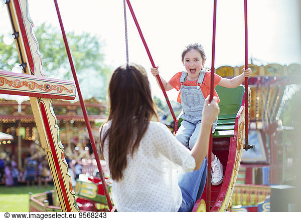 Mother and daughter playing on swing in amusement park