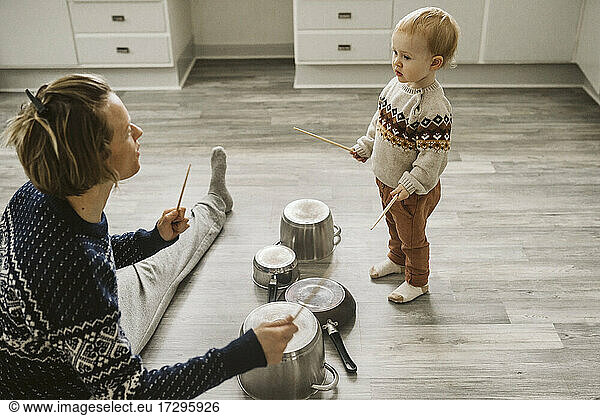 Mother and daughter playing with chopsticks and utensils in kitchen