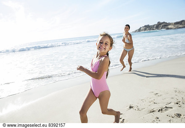 Mother and daughter running on beach