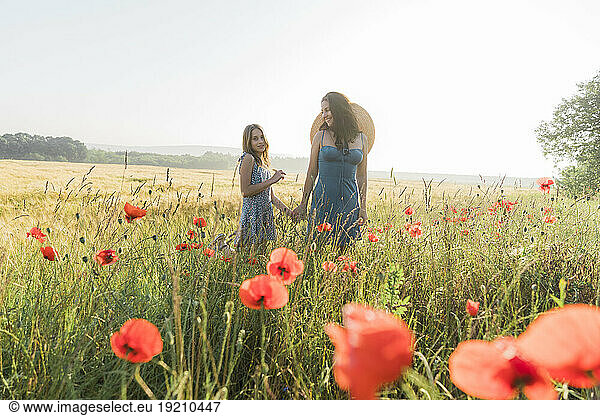 Mother and daughter spending leisure time in poppy field