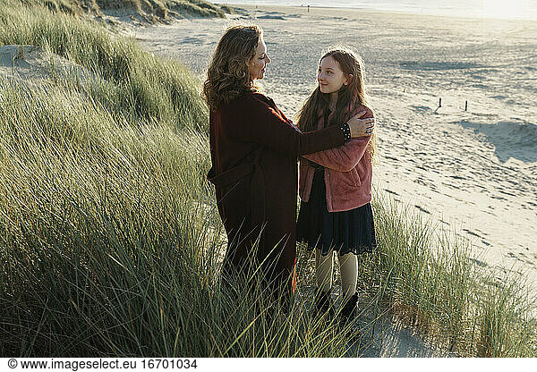 Mother and daughter standing on the beach against seascape view