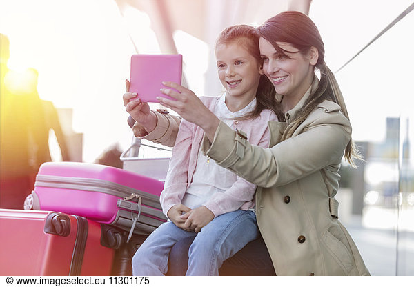 Mother and daughter taking selfie with digital tablet camera at airport