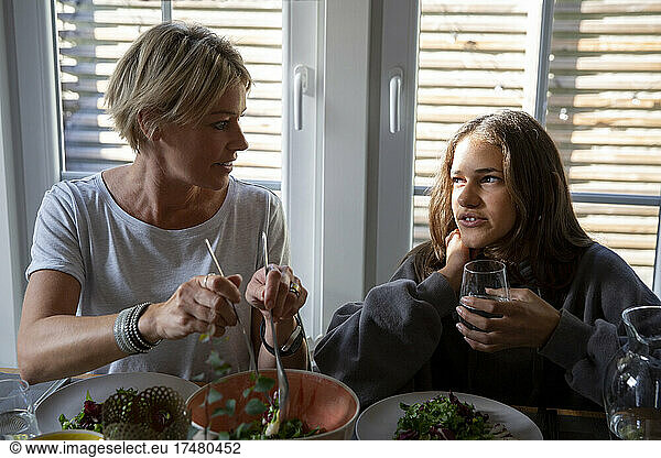 Mother and daughter talking while eating dinner at home