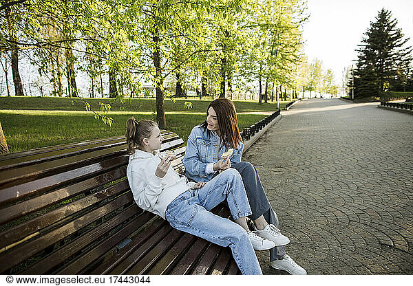 Mother and daughter talking while having food at park