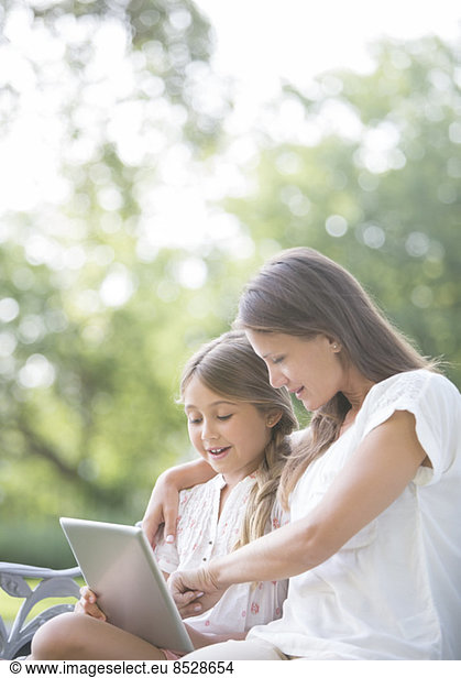 Mother and daughter using digital tablet outdoors