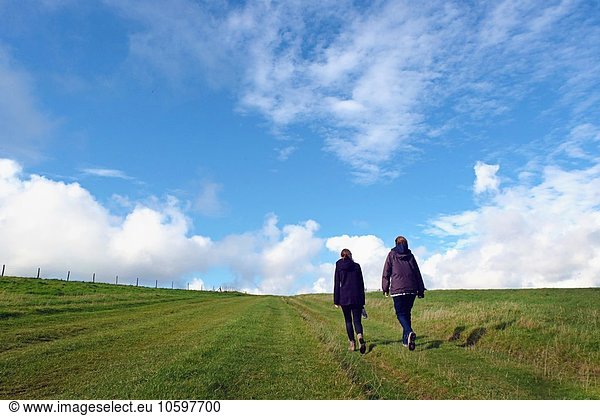 Mother and daughter walking in field  rear view  South Downs  East Sussex  UK