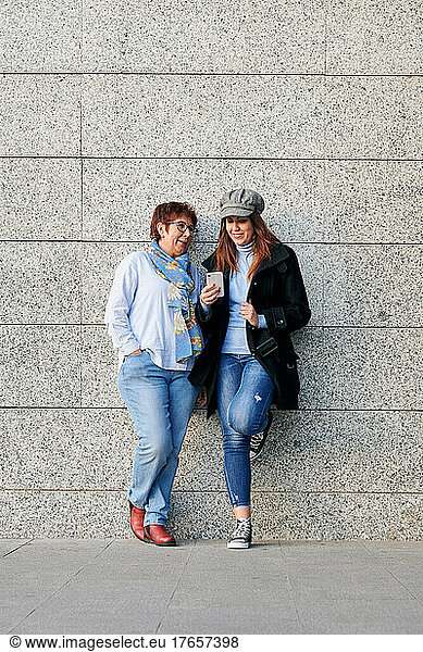 Mother and daughter with a phone and casual clothes in the street