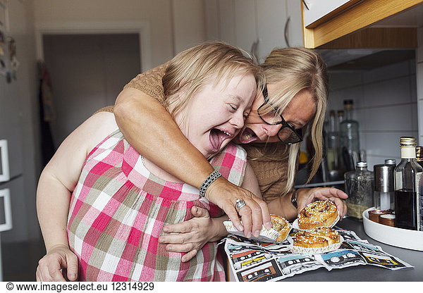Mother and daughter with down syndrome about to eat pastry in kitchen