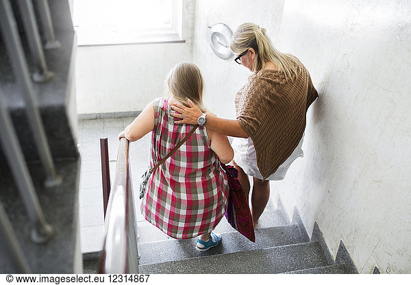 Mother and daughter with down syndrome walking down stairs