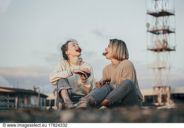 Mother and daughter with strawberries in mouth enjoying at beach