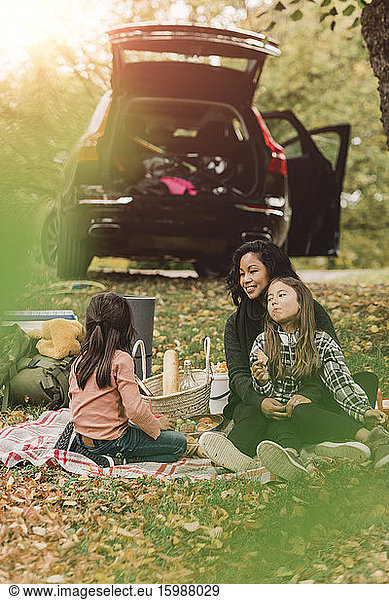 Mother and daughters enjoying picnic in autumn