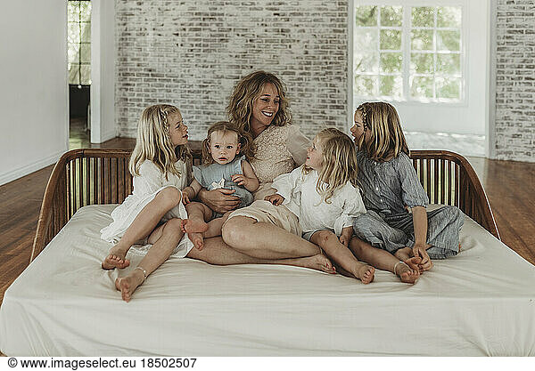Mother and daughters looking at each other lovingly on studio couch