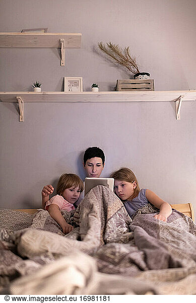 Mother and daughters watching film before sleep