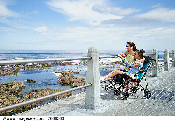 Mother and disabled daughter in pushchair at ocean boardwalk