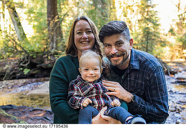 Mother and father holding their son outdoors in nature.