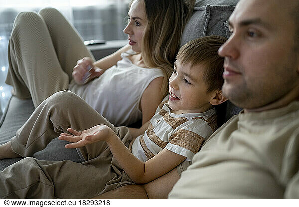 Mother and father with son watching TV at home