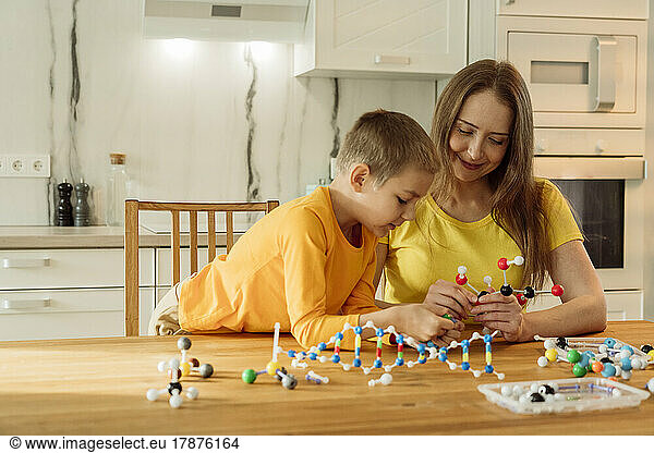 Mother and son constructing molecular structure on table at home