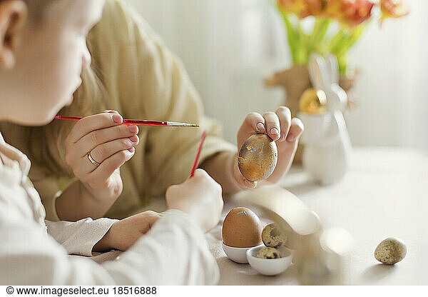 Mother and son decorating Easter eggs at home