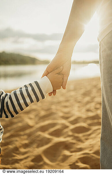 Mother and son holding hands at beach