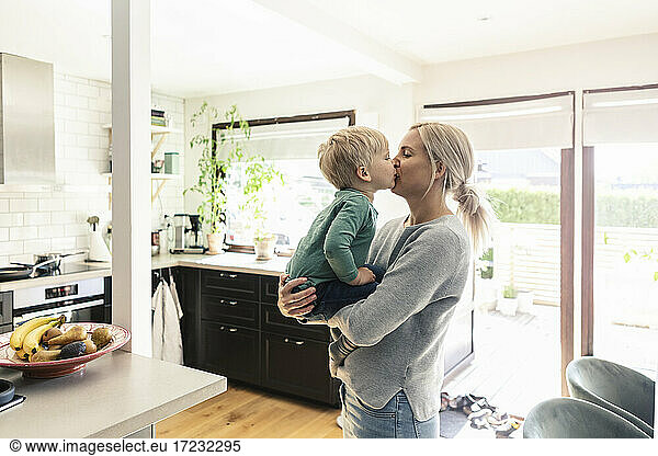 Mother and son kissing each other in kitchen at home