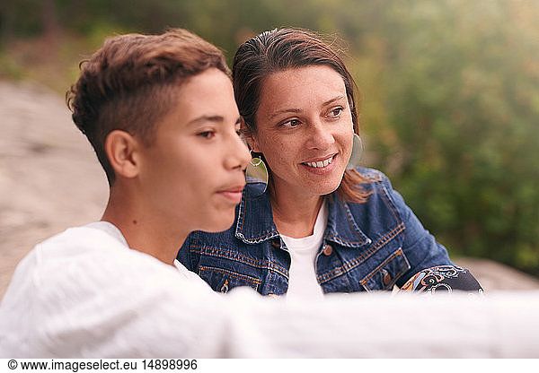 Mother and son looking away while sitting in park