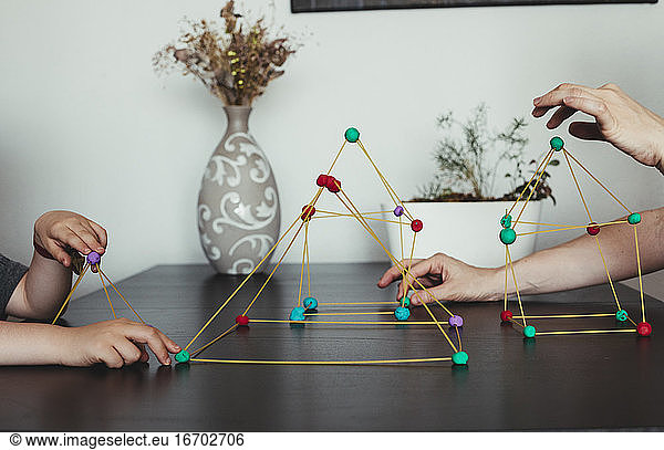 Mother and son making geometric shapes from sticks and play dough.