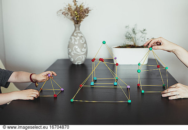 Mother and son making geometric shapes from sticks and play dough.