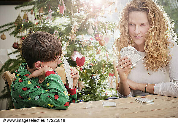 Mother and son playing cards at table during Christmas