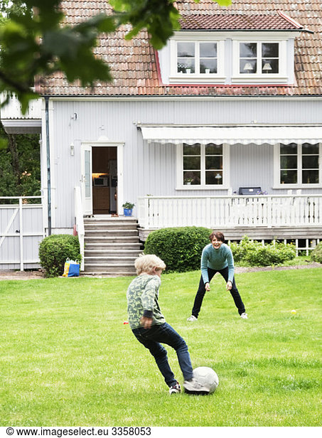 Mother and son playing soccer in garden