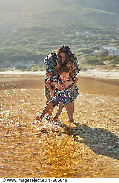 Mother and son playing  splashing in sunny ocean surf