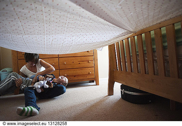 Mother and son playing under textile in bedroom