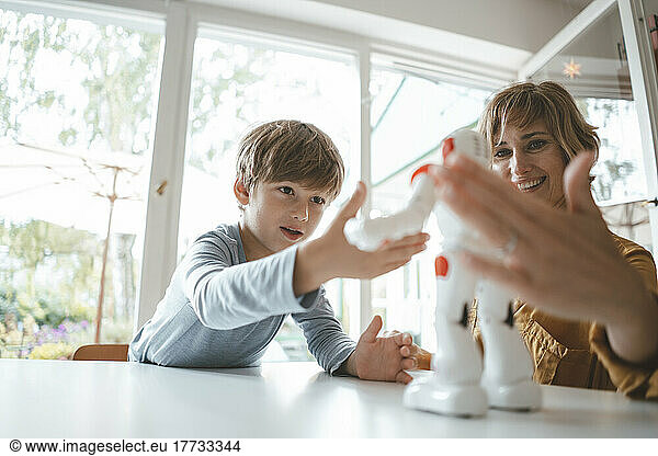 Mother and son playing with toy robot at home