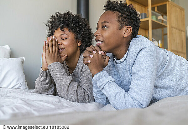 Mother and son praying by bed at home