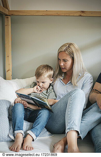 Mother and son reading book in bedroom