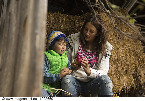 Mother and son sitting on straw in the stable