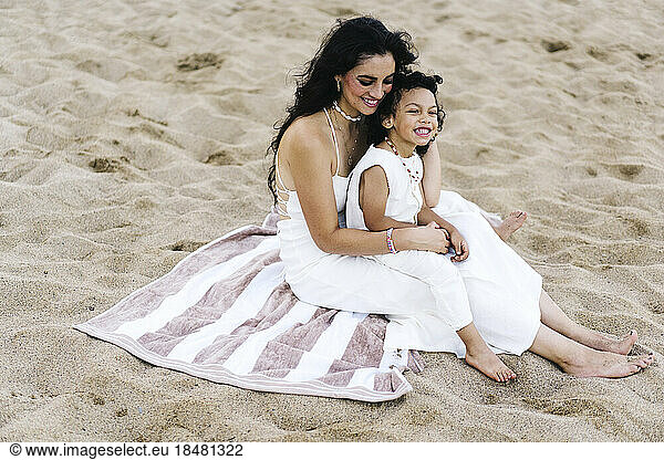 Mother and son sitting on towel at beach