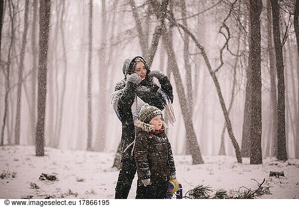 Mother and son standing in park during snowfall in winter
