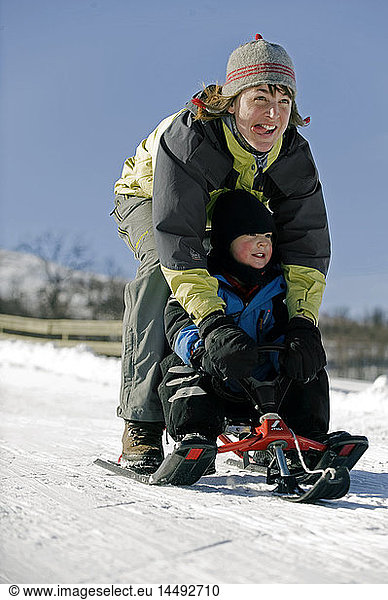 Mother and son tobogganing in snow