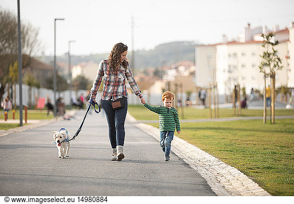Mother and son walking with pet puppy on quiet road