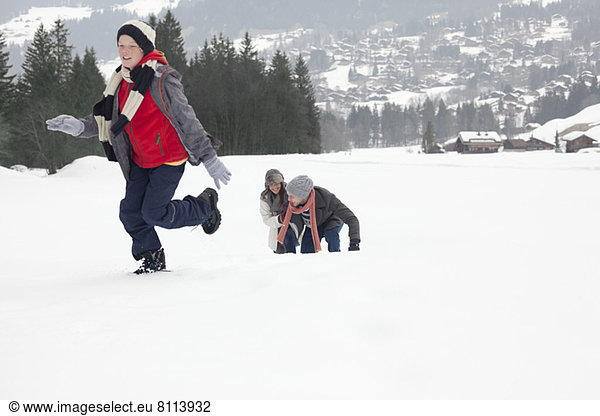 Mother and sons playing in snowy field