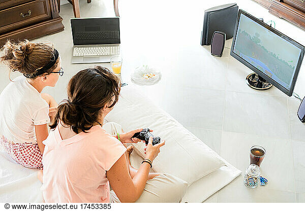 Mother and teen girl playing video games together at weekend at home
