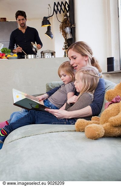 Mother and two daughters reading storybook