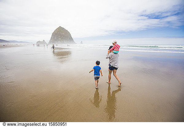Mother and two kids walk toward Haystack Rock  Cannon Beach.