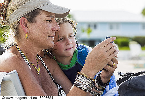 mother and 5 year old son looking at smart phone at the beach