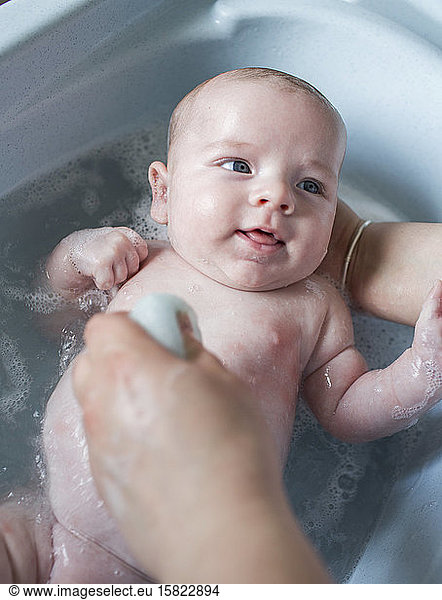 Mother bathing her baby boy in a tub