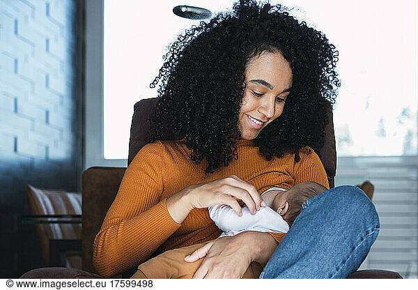 Mother breastfeeding baby boy at home